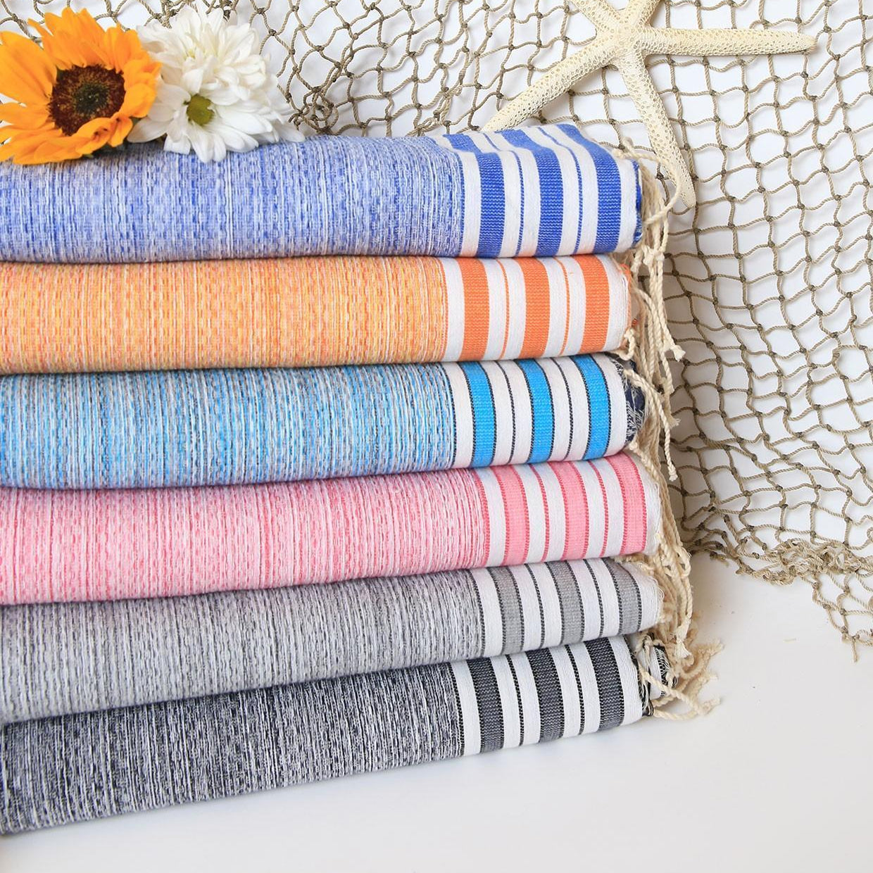 Stack of colorful towels with a starfish and sunflower against a textured net background